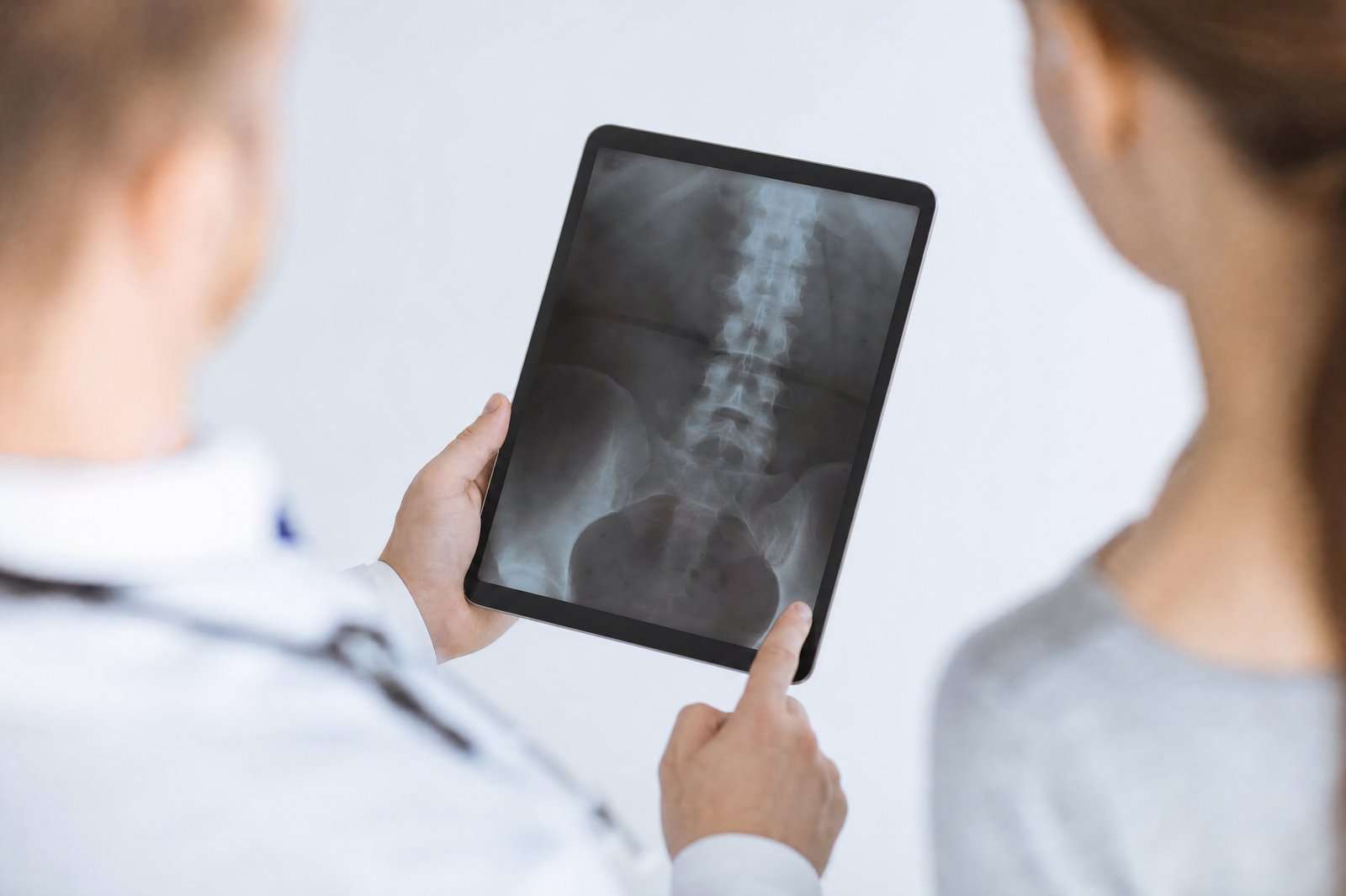 Chiropractor reviewing a lumbar spine X-ray with a patient on a tablet at a Holland, MI clinic